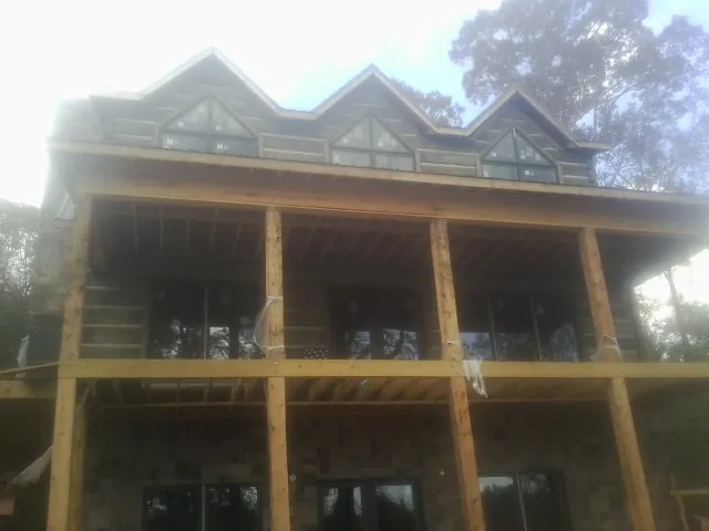 Dormers and porch framing on a large log home under construction — Roof Coating work by our crew in Casco