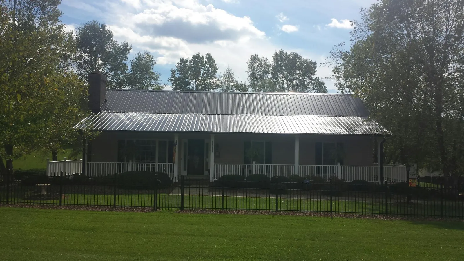 Gray metal roof on a brick ranch with a full width front porch — Gutter Guard Installation work by our crew in Casco