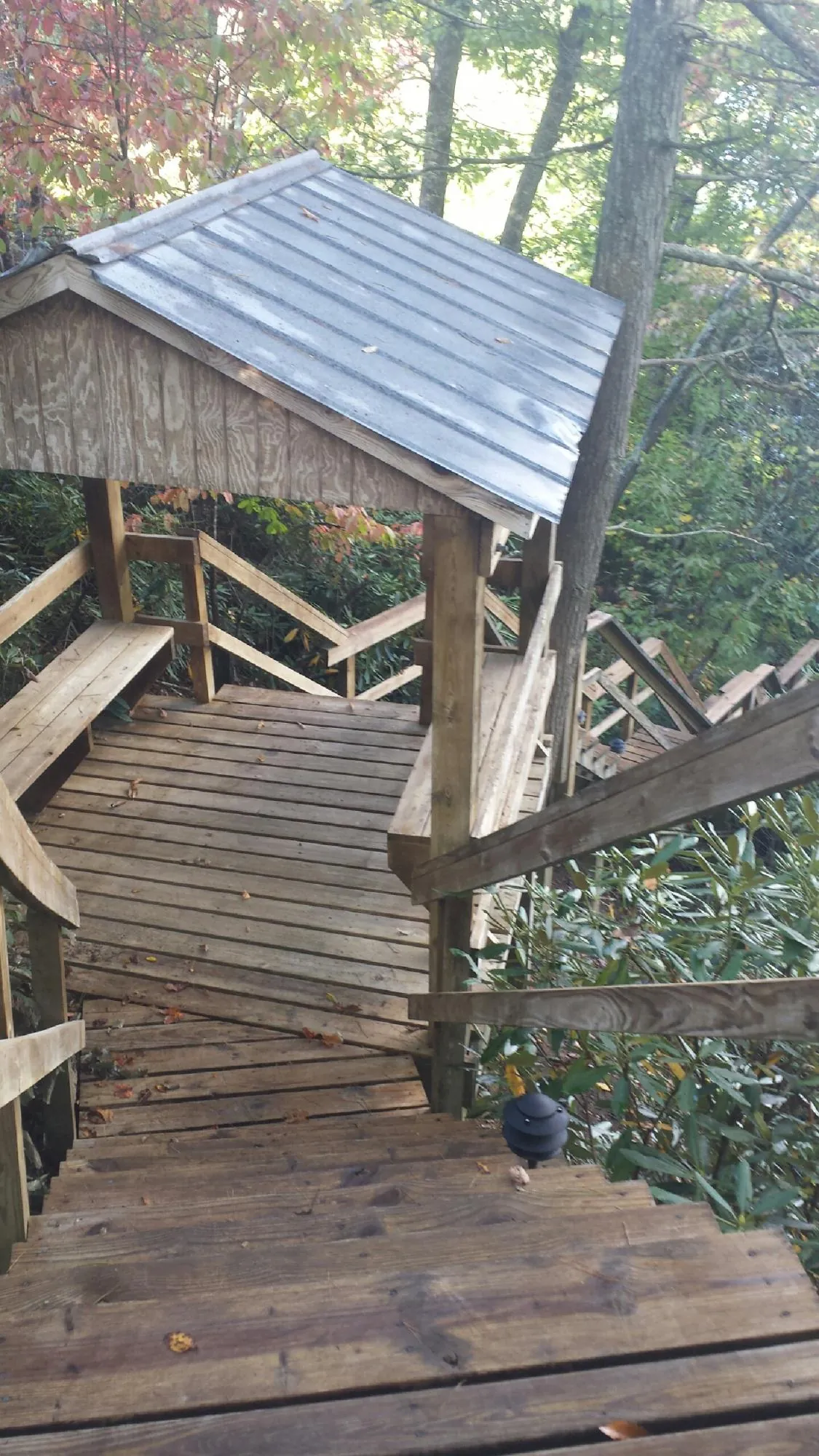 Metal roofed shelter over wooden steps on a wooded walkway — Skylight Repair & Installation work by our crew in Casco
